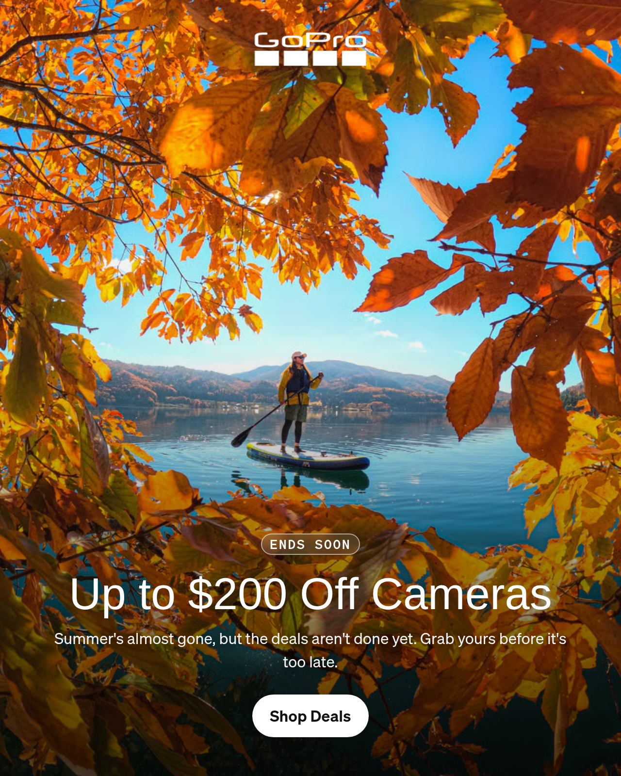 Person paddleboarding on a lake framed by autumn foliage.