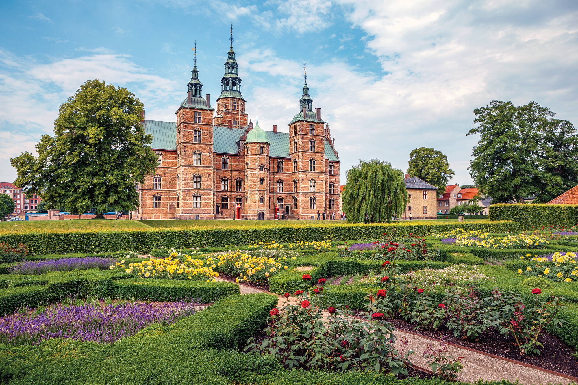 Rosenborg Castle and Gardens in Copenhagen, Denmark, with blooming flowers and green hedges.