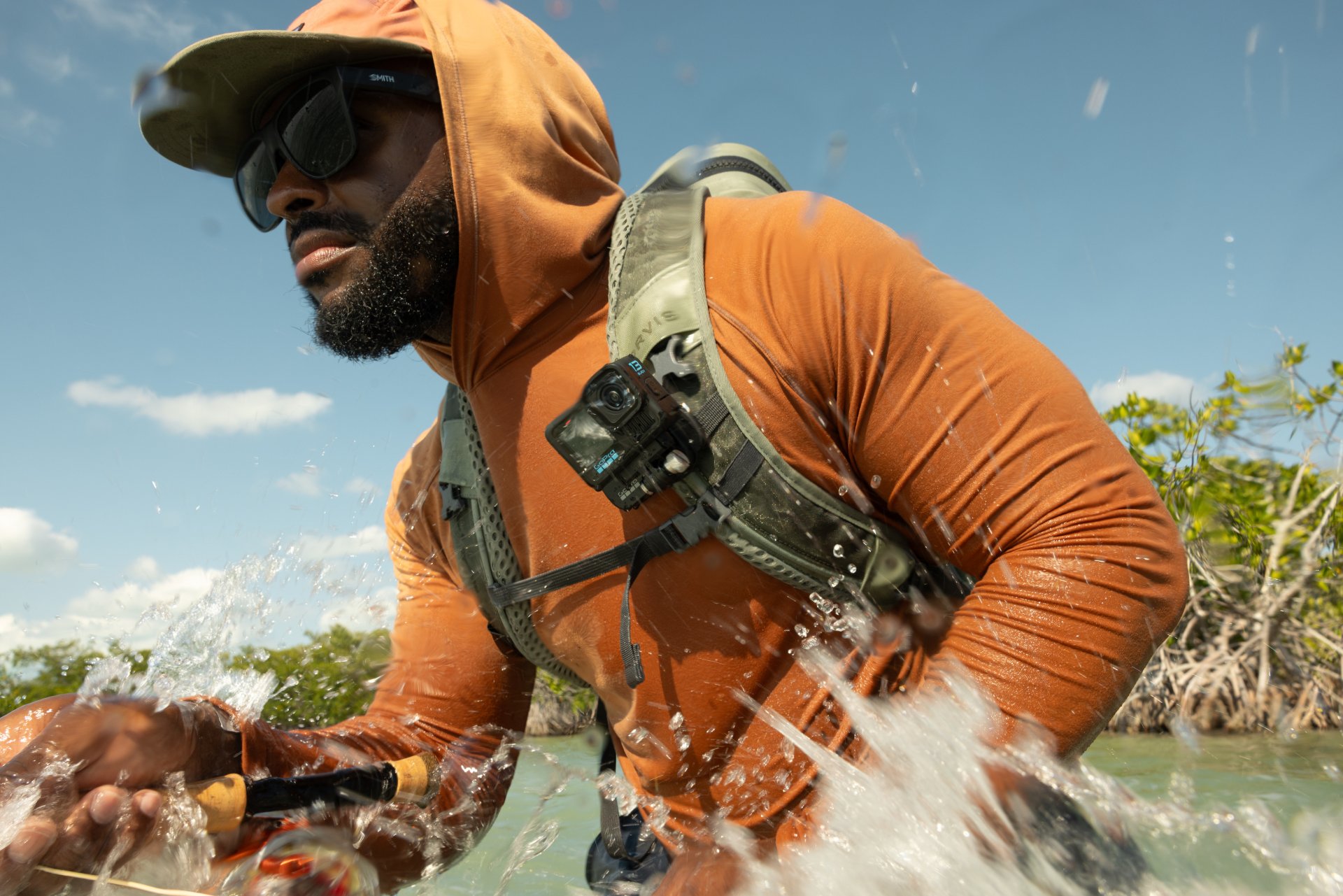 A fly fisherman with a chest-mounted GoPro action camera moving through water.