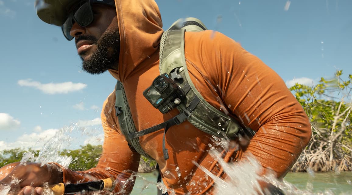 A fly fisherman with a chest-mounted GoPro action camera moving through water.