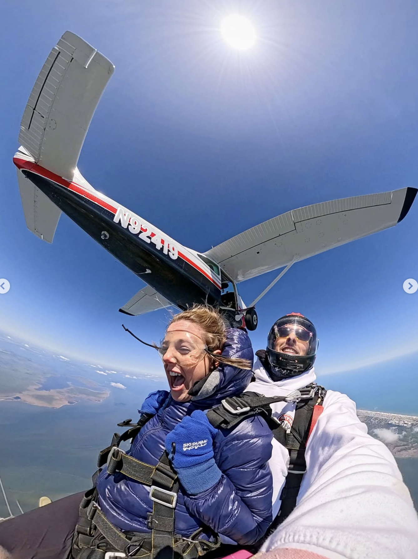 A tandem skydiver and a client captured mid-air with an airplane in the background.