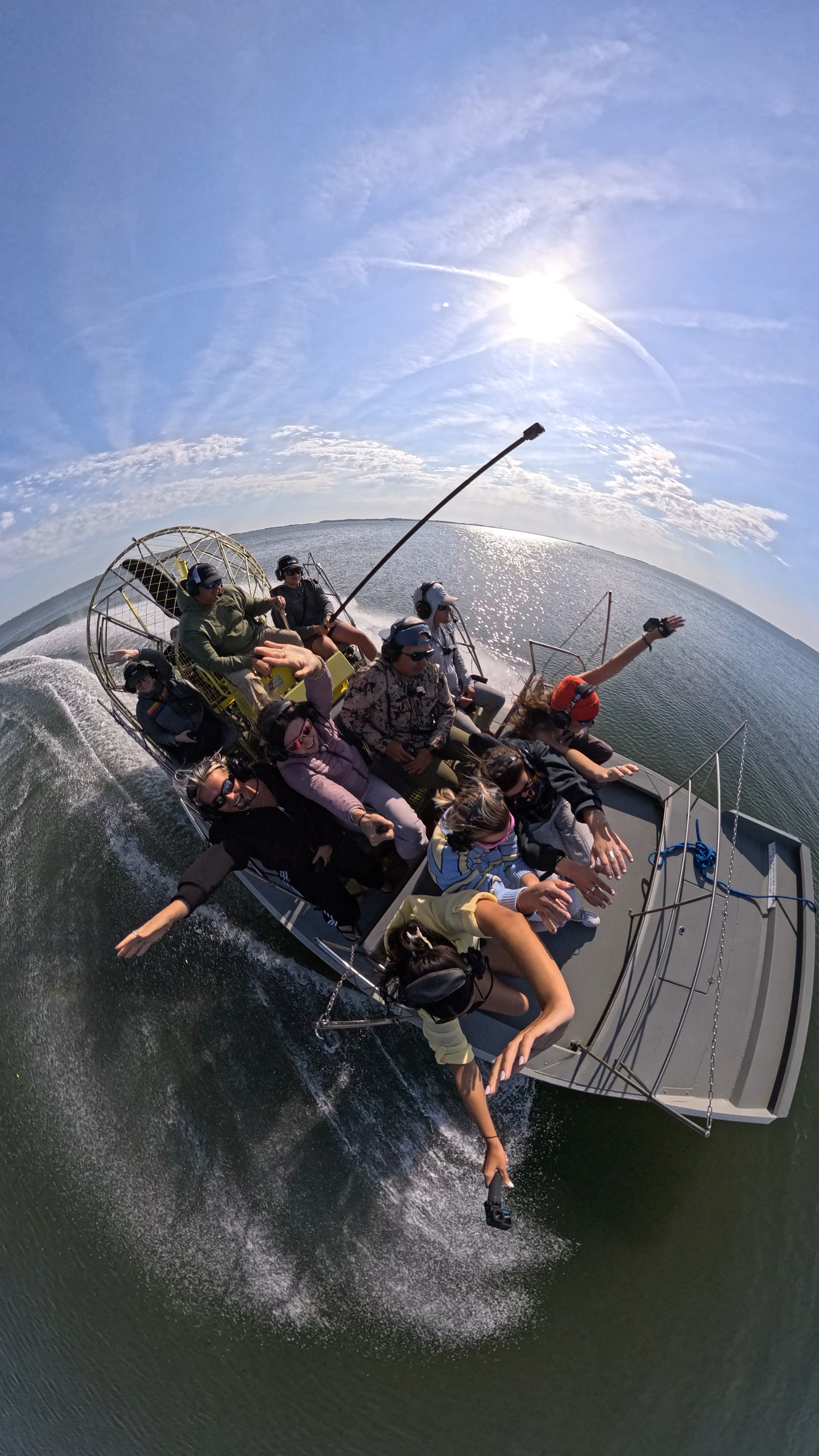 An angler wading in shallow surf holds up a freshly caught fish next to a fly rod and tackle.